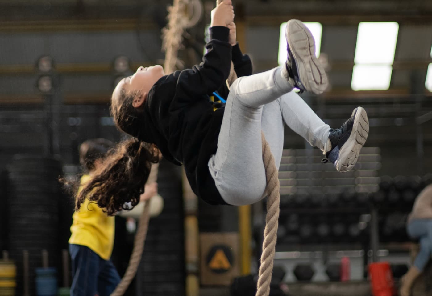 Una niña trepando la cuerda durante una clase de Acción Kids