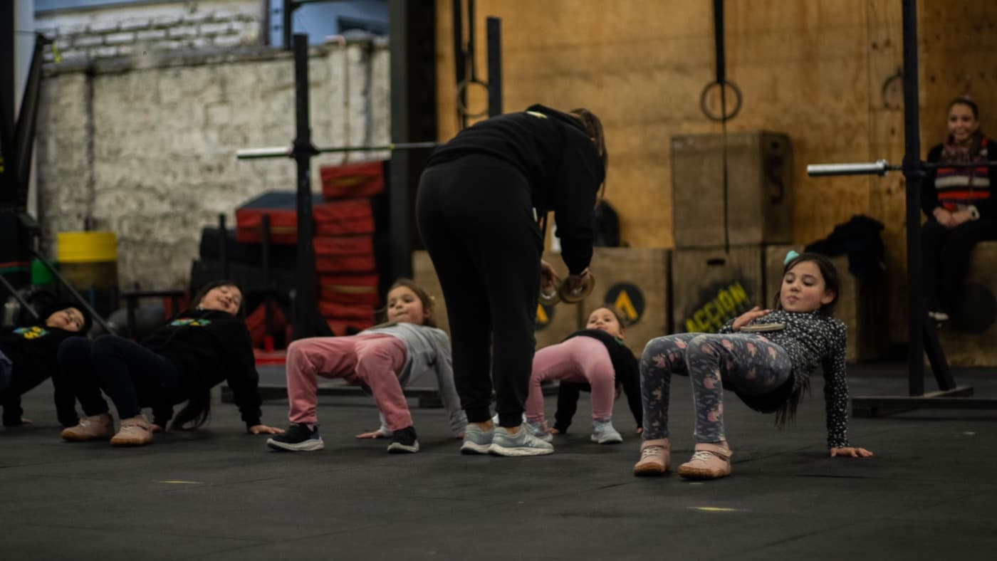 Niñas y niños haciendo un ejercicio de movimiento guiados por su coach