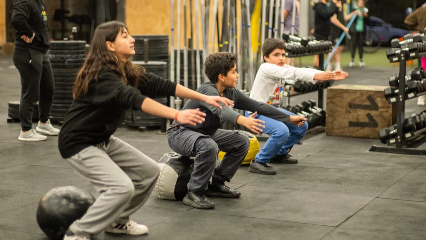 Un grupo de niños haciendo sentadillas en una clase de Acción Kids